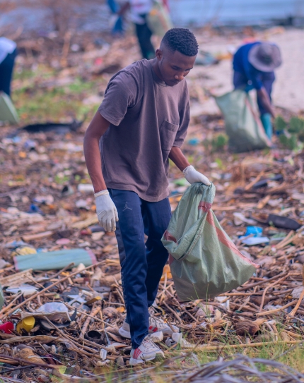 Member of Blue Vision Tanzania picking up litter alng seashore